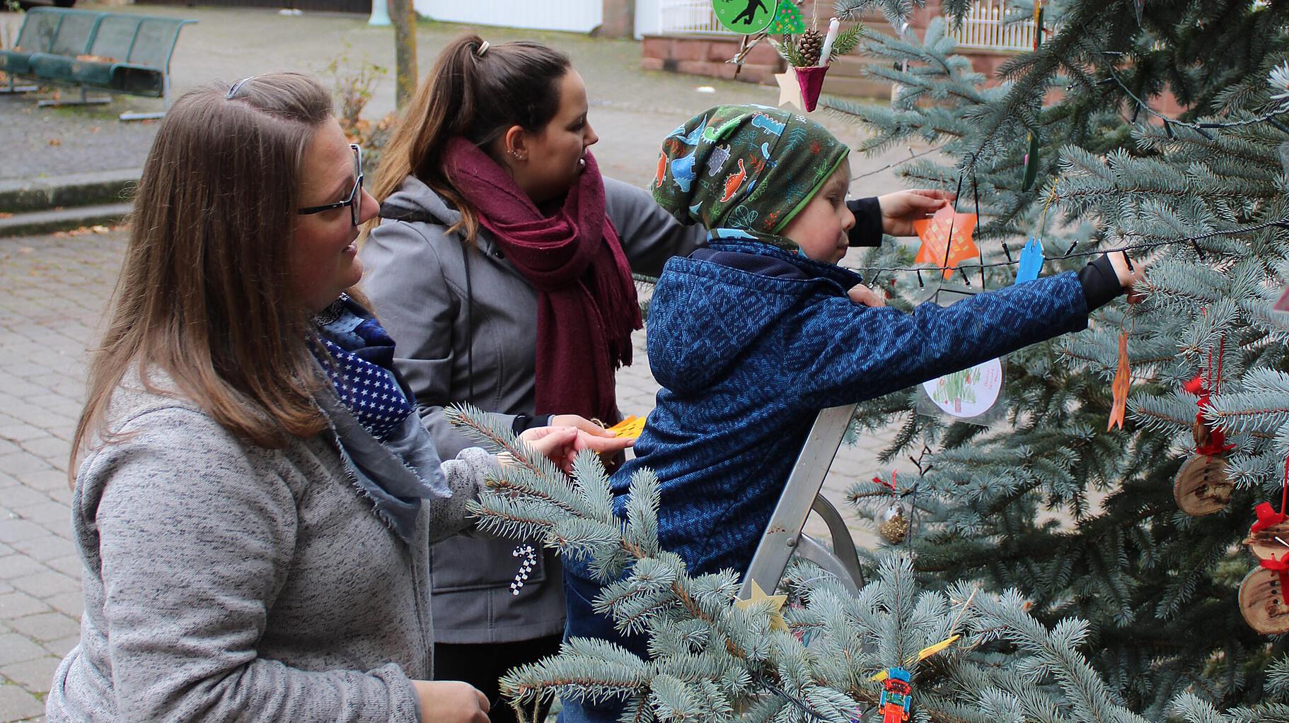 Kinder schmücken den Weihnachtsbaum am Marktplatz